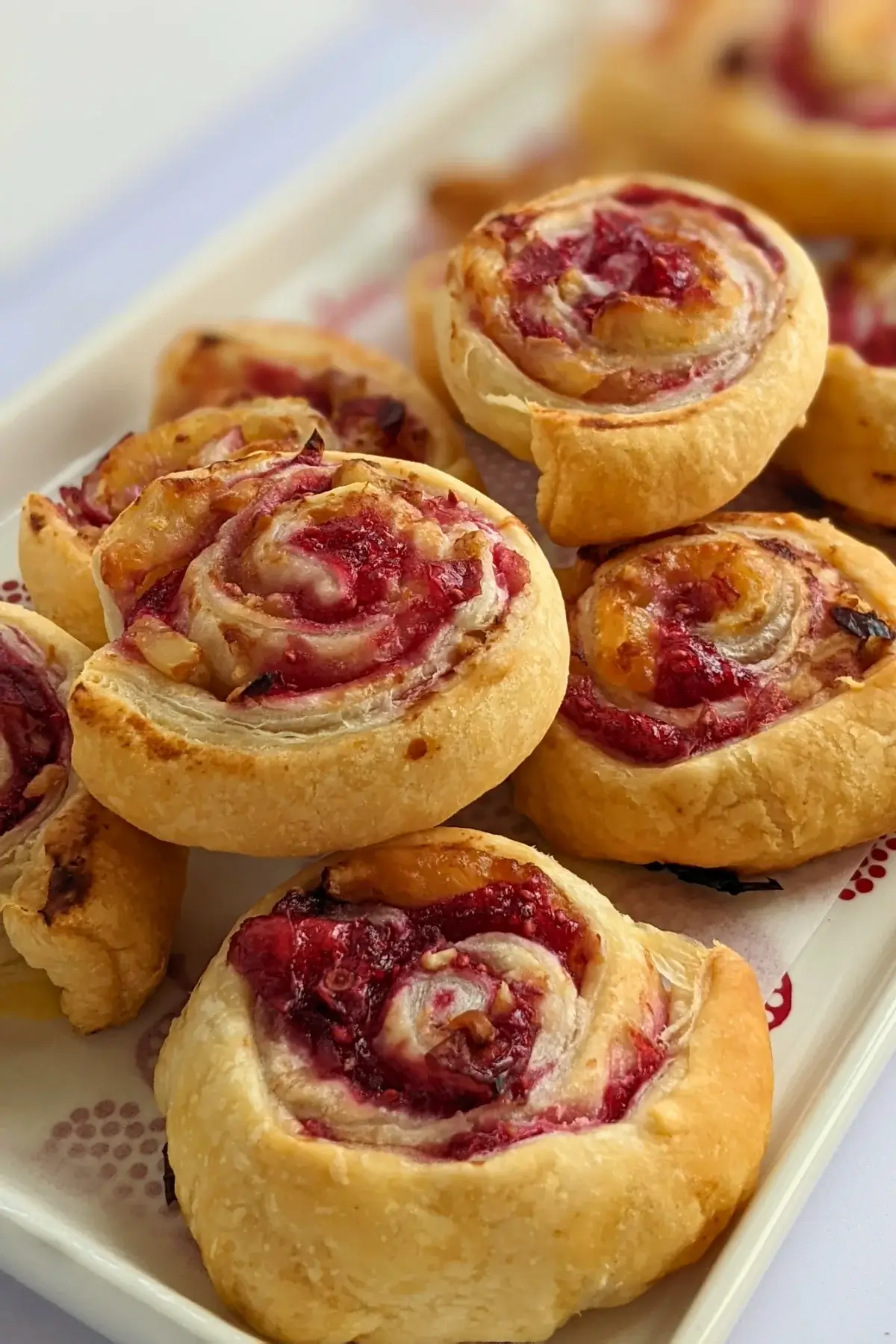 Flaky cranberry brie pinwheel bites with puff pastry filled with melted brie and tart homemade cranberry sauce plus walnuts.