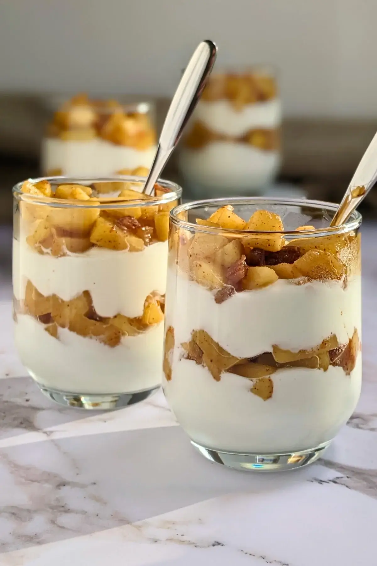 Healthy layered apple parfait dessert with whipped ricotta and cream, topped with stewed apples and chopped dates.