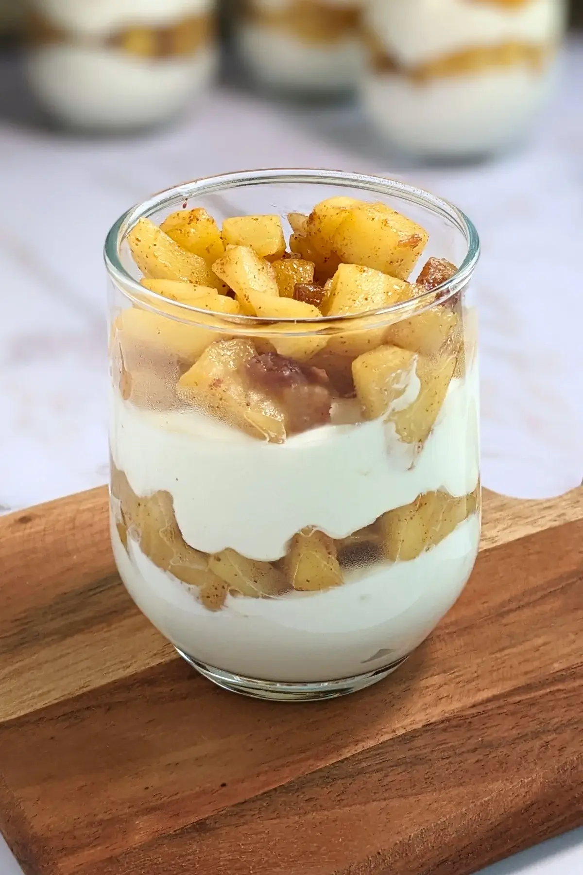 Healthy layered apple parfait dessert with whipped ricotta and cream, topped with stewed apples and chopped dates.