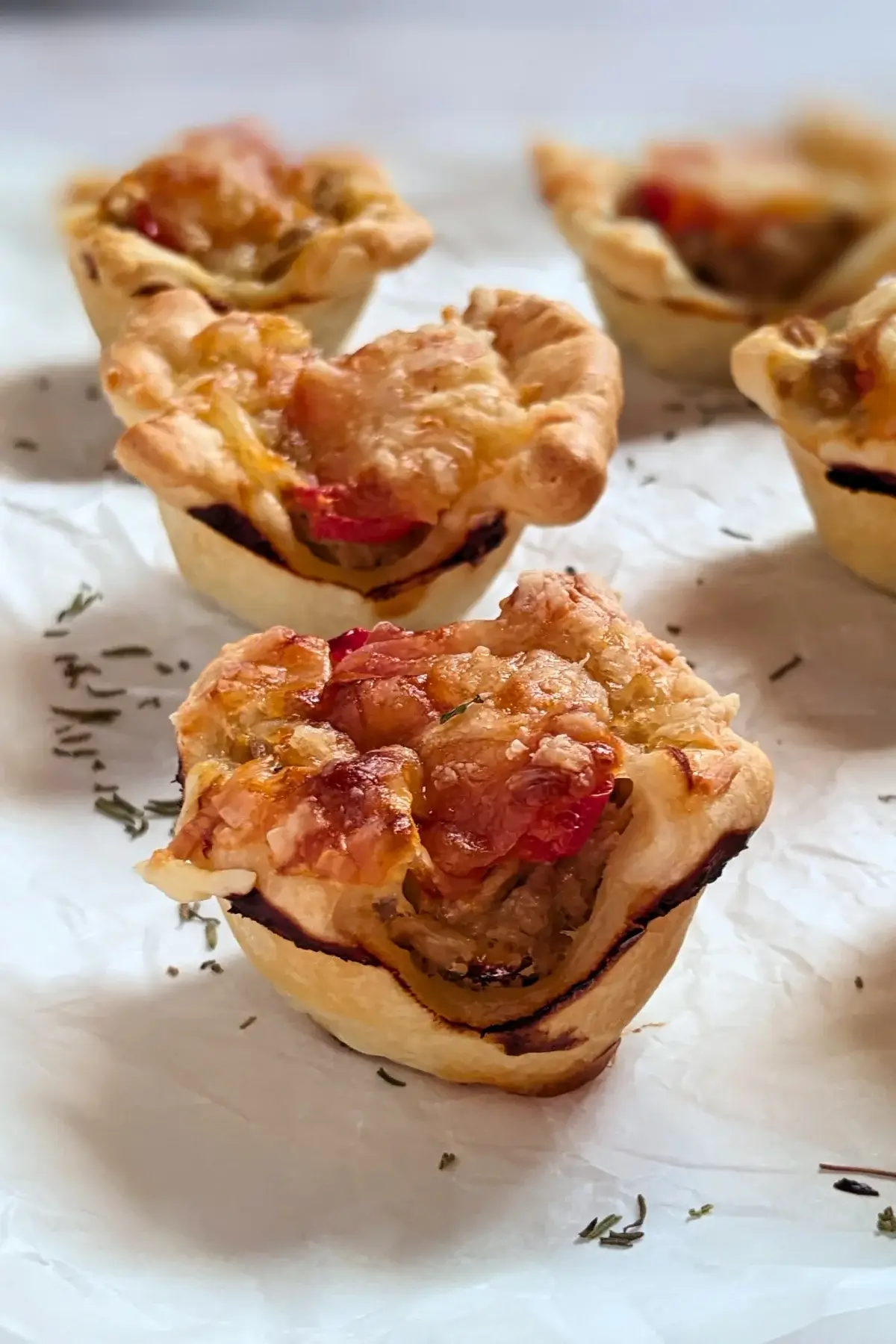 Mini Tuna Tart Cups With Puff Pastry - mini tuna tart appetizers made in a mini muffin tin with a canned tuna and sour cream filling and grated cheese topping in puff pastry cups.