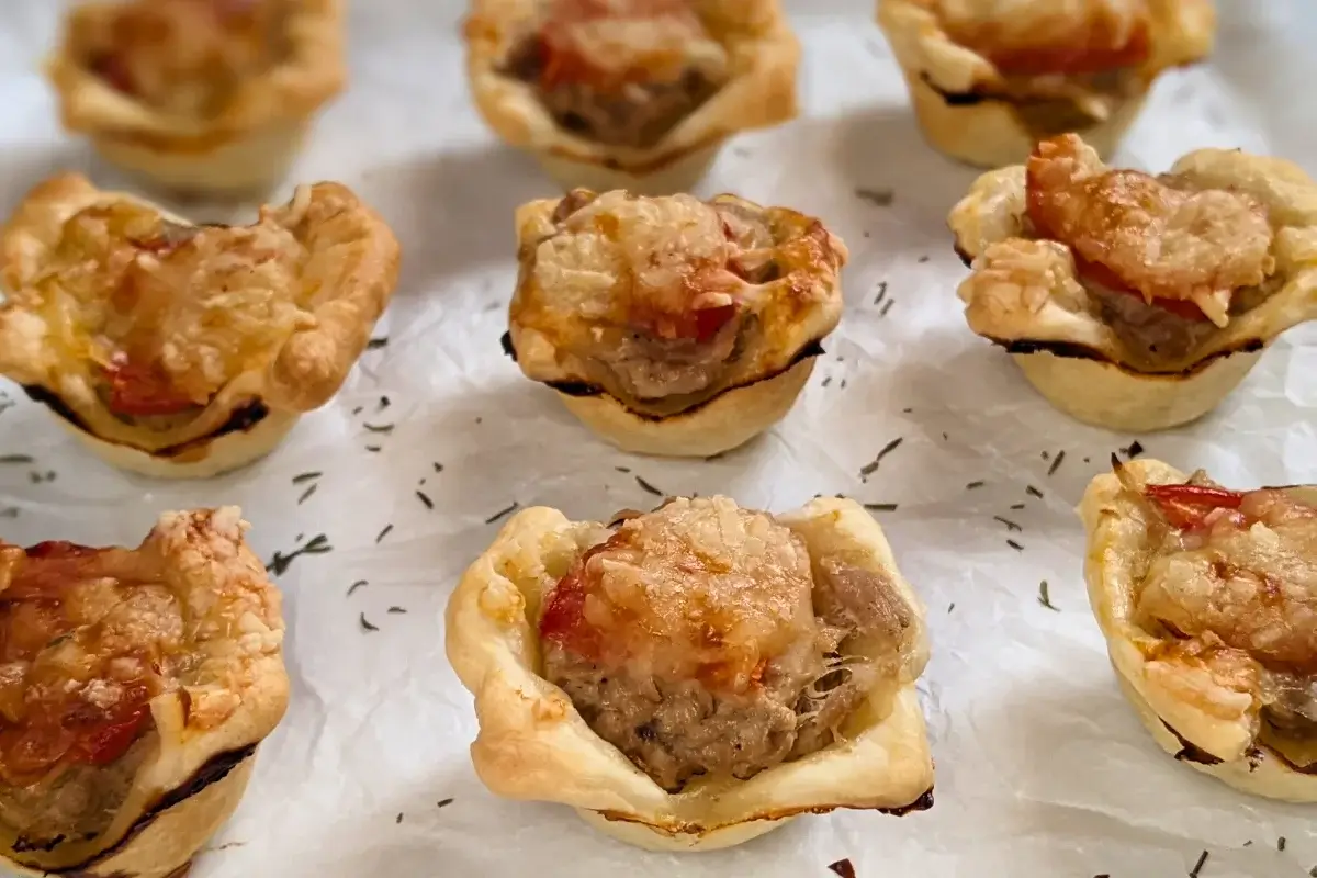 Mini Tuna Tart Cups With Puff Pastry - mini tuna tart appetizers made in a mini muffin tin with a canned tuna and sour cream filling and grated cheese topping in puff pastry cups.
