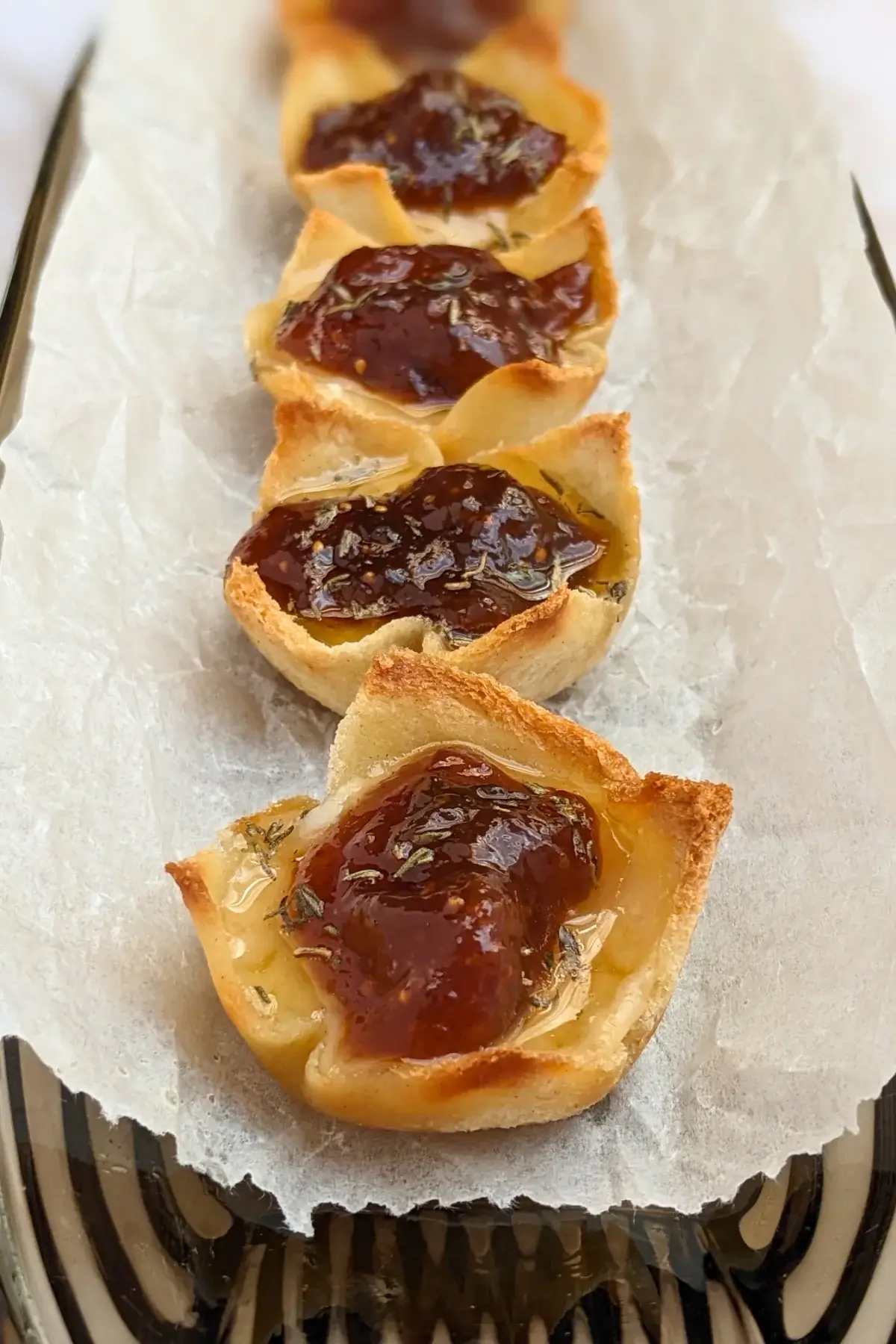 Parmesan cheese and fig jam appetizer bites - mini bread toast cups filled with parmesan cheese, topped with fig jam and a honey-dryed thyme drizzle.