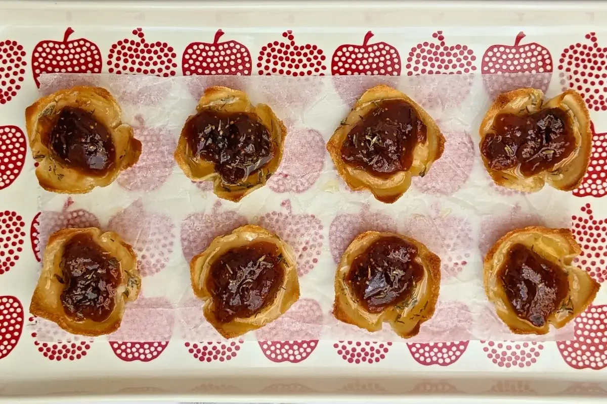 Parmesan cheese and fig jam appetizer bites - mini bread toast cups filled with parmesan cheese, topped with fig jam and a honey-dryed thyme drizzle.