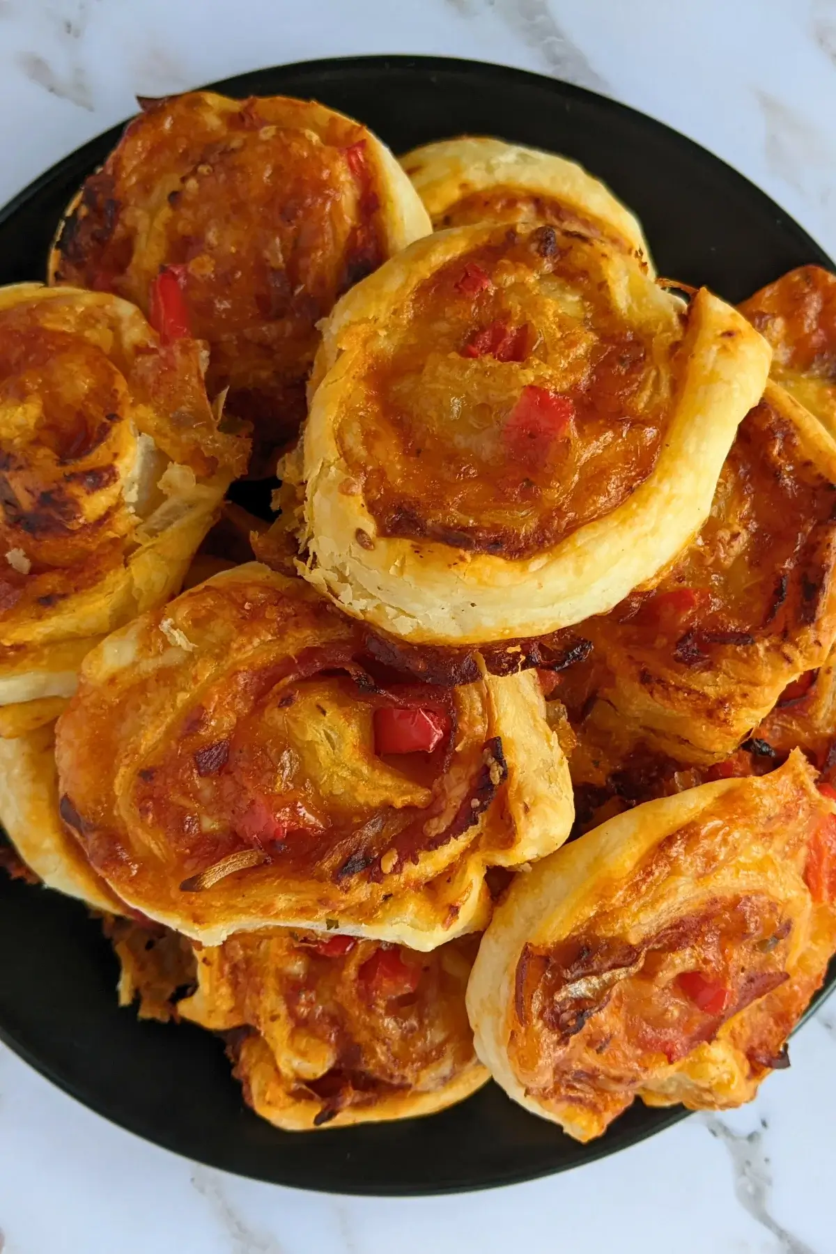 Golden brown pizza pinwheels filled with tomato sauce, salami, and melted cheese.