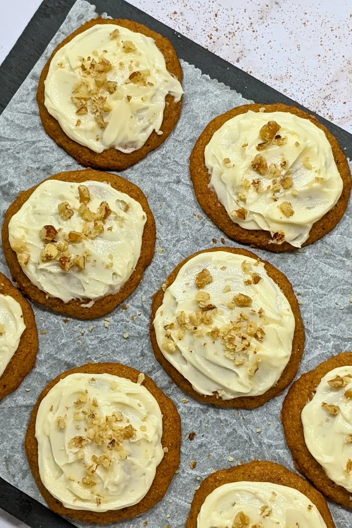 Pumpkin cookies with cream cheese icing made partly with healthier wholemeal flour and coconut sugar, frosted with a cream cheese icing and topped with crushed walnuts for decoration.