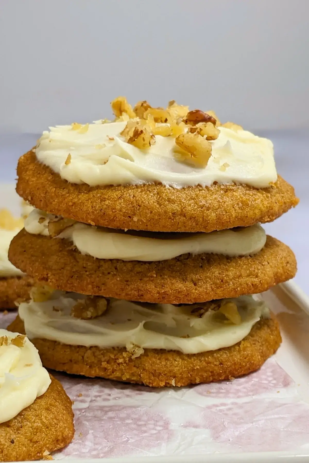 Pumpkin cookies with cream cheese icing made partly with healthier wholemeal flour and coconut sugar, frosted with a cream cheese icing and topped with crushed walnuts for decoration.