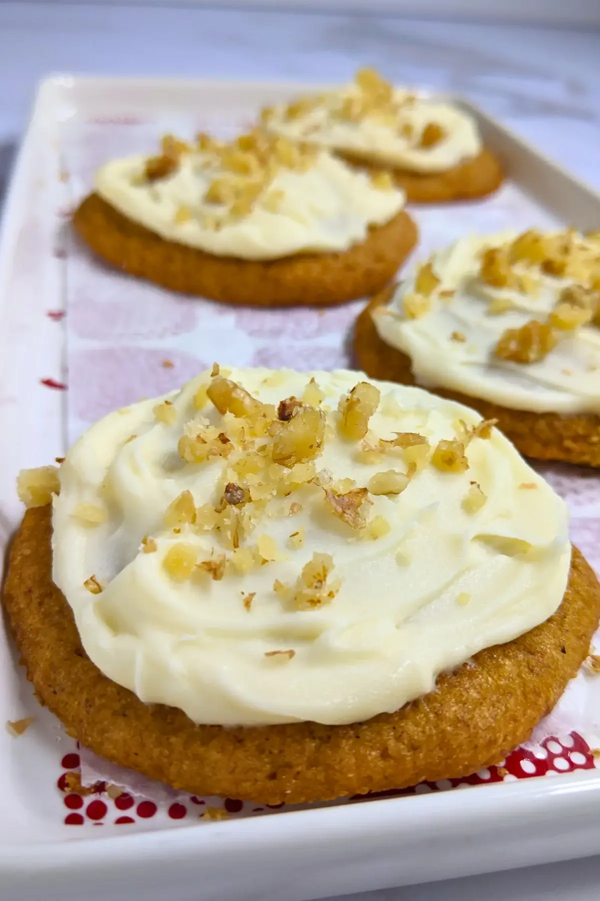Pumpkin cookies with cream cheese icing made partly with healthier wholemeal flour and coconut sugar, frosted with a cream cheese icing and topped with crushed walnuts for decoration.