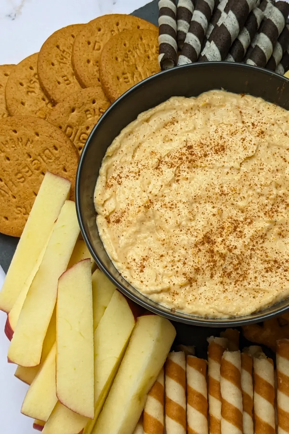 Pumpkin dip with cream cheese, cinnamon, pumpkin pie spice and Greek yogurt served with sliced apples and pears, vanilla wafer sticks, biscuits, and pretzels.
