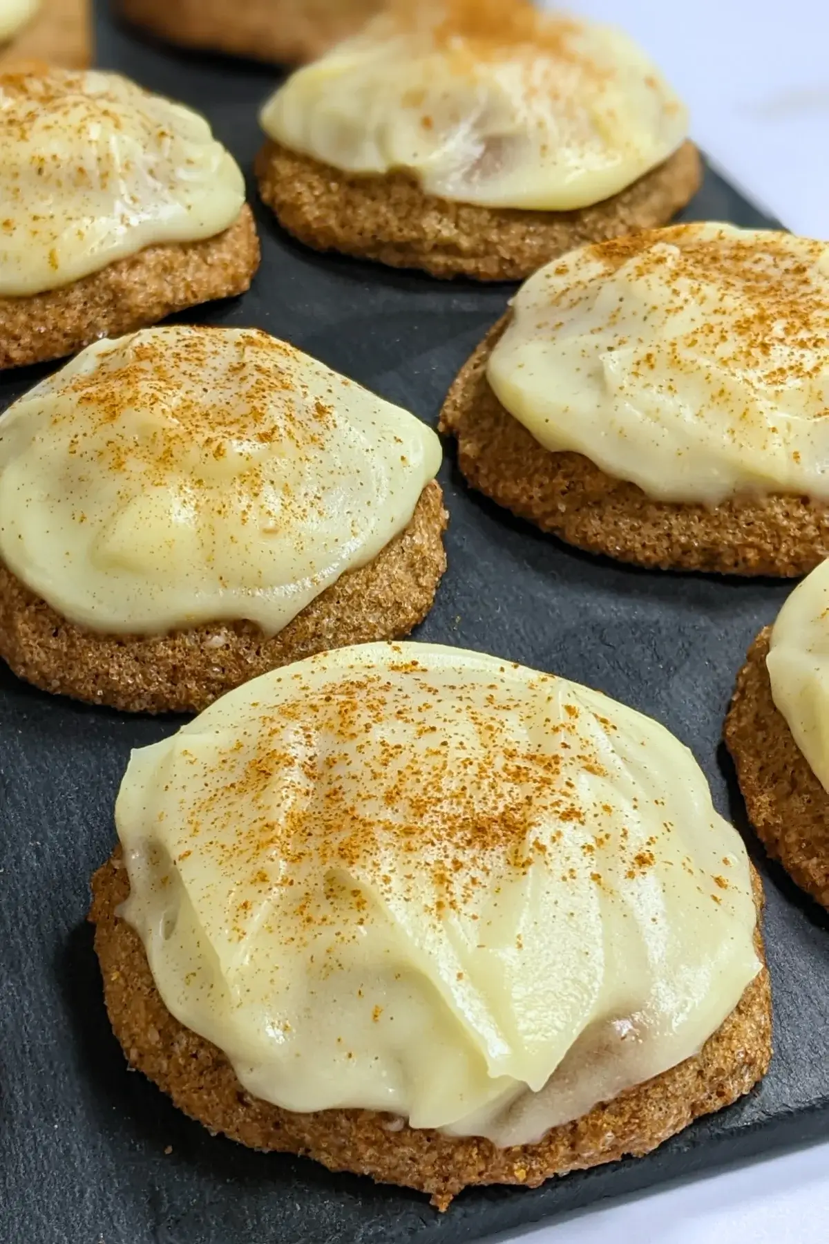 Pumpkin sugar cookies made with healthier wholemeal flour and coconut sugar, frosted with a classic cream cheese icing, and decorated with sprinkles of cinnamon.