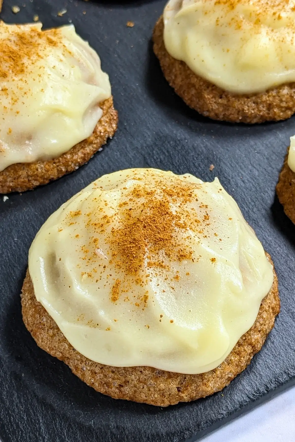 Pumpkin sugar cookies made with healthier wholemeal flour and coconut sugar, frosted with a classic cream cheese icing, and decorated with sprinkles of cinnamon.