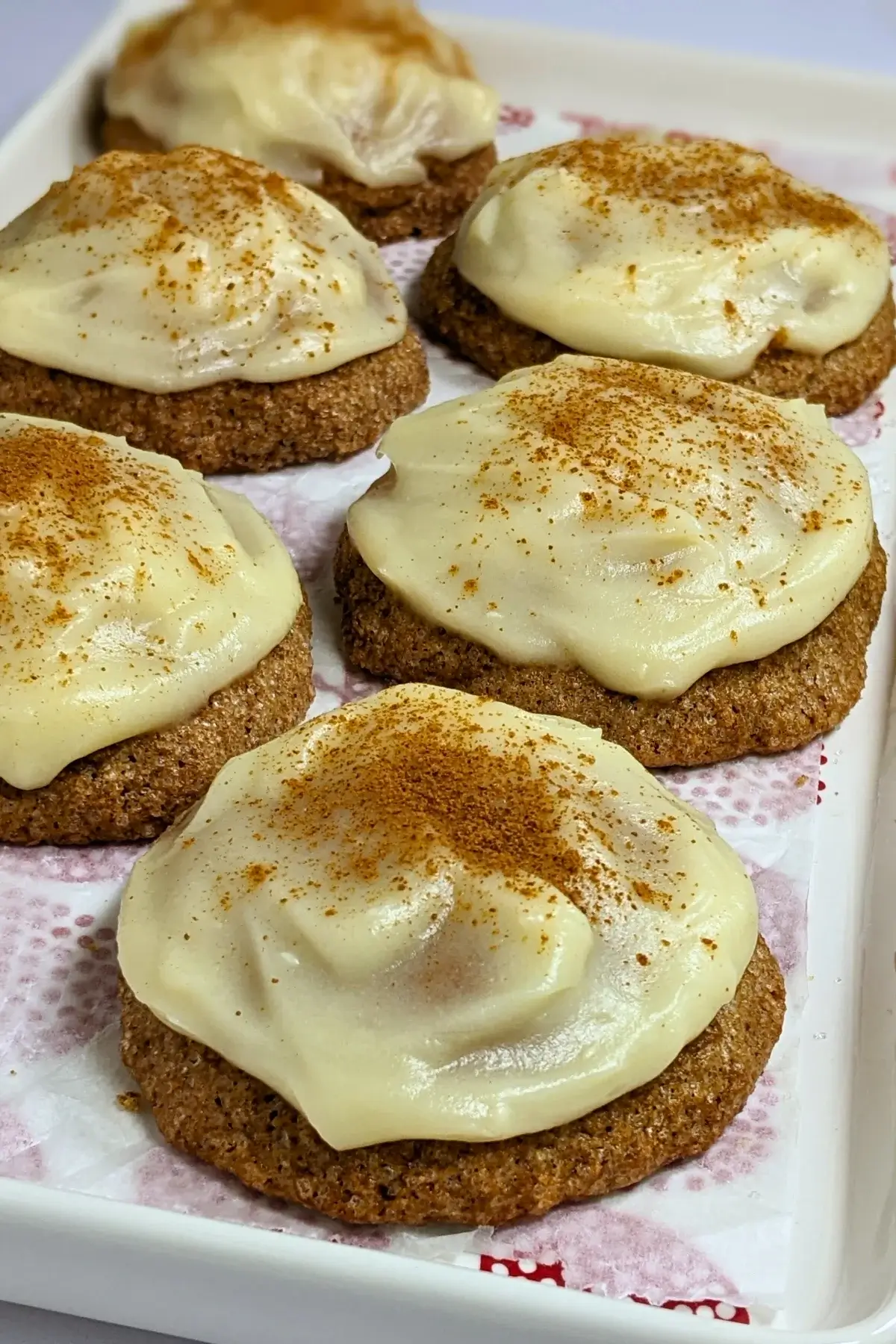Pumpkin sugar cookies made with healthier wholemeal flour and coconut sugar, frosted with a classic cream cheese icing, and decorated with sprinkles of cinnamon.