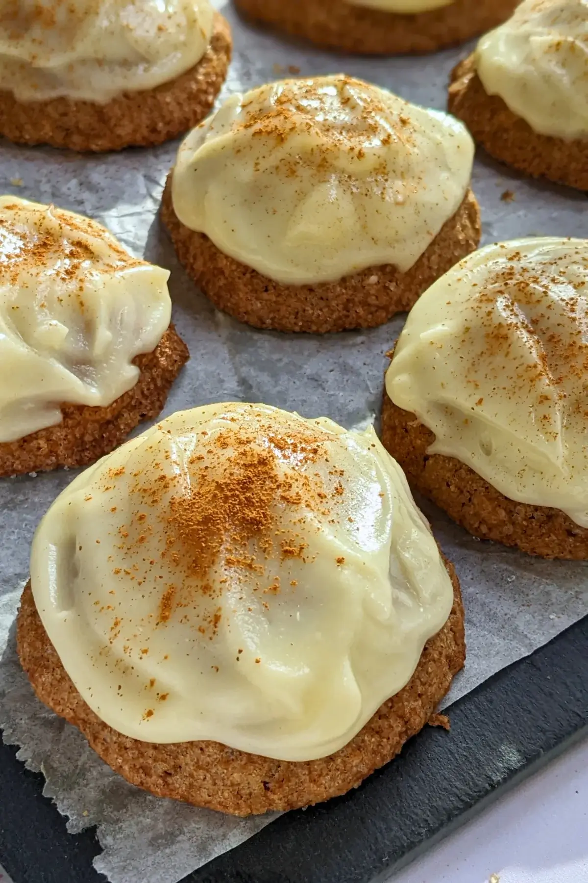 Pumpkin sugar cookies made with healthier wholemeal flour and coconut sugar, frosted with a classic cream cheese icing, and decorated with sprinkles of cinnamon.
