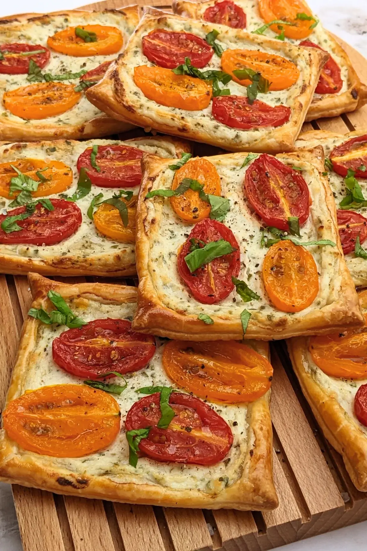 Roasted cherry tomato tarts with puff pastry - a puff pastry appetizer filled with ricotta and parmesan and topped with red and yellow cherry tomatoes and basil.
