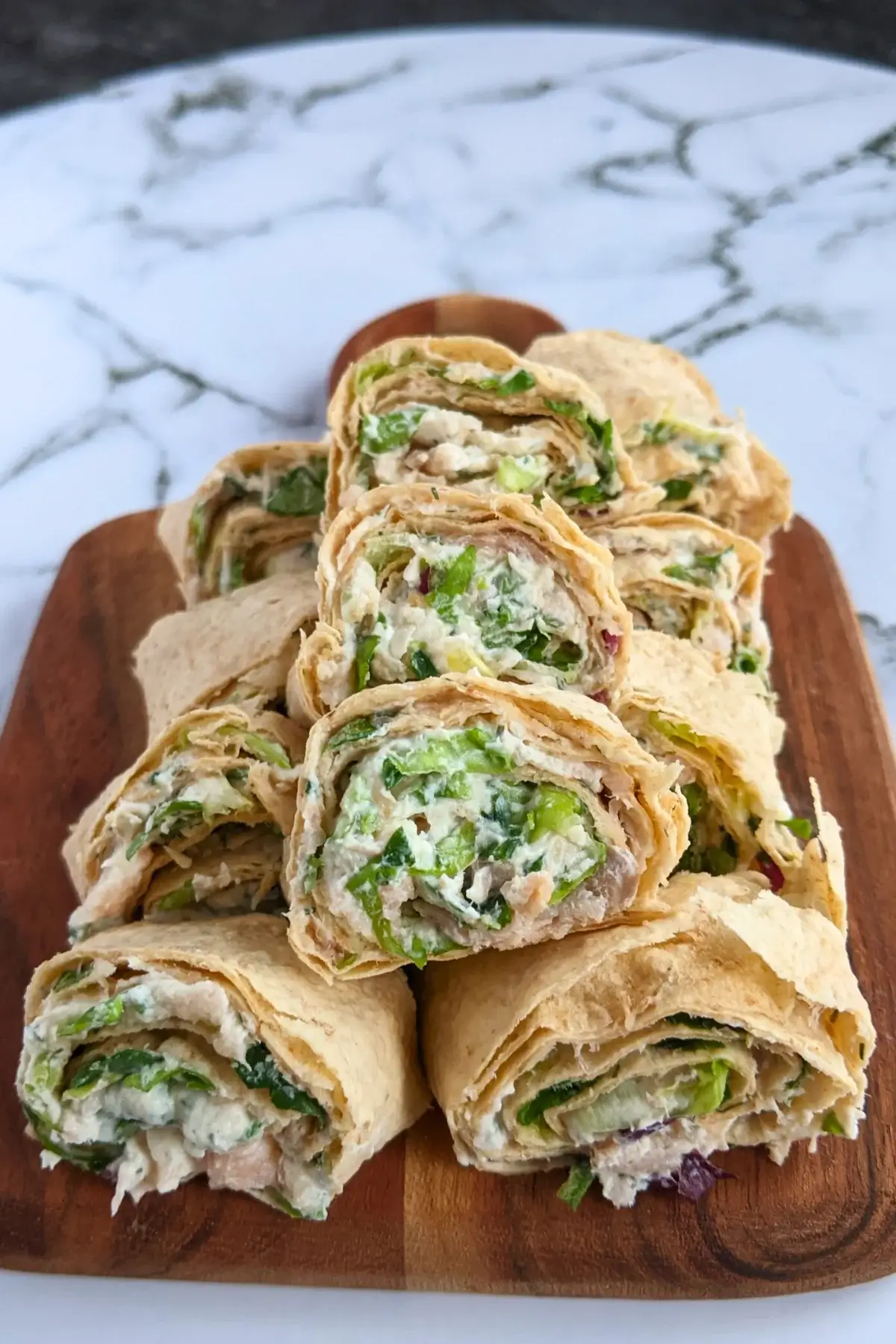 Smoked salmon flatbread rolls sliced into pinwheels filled with salmon-cream cheese spread and fresh greens.