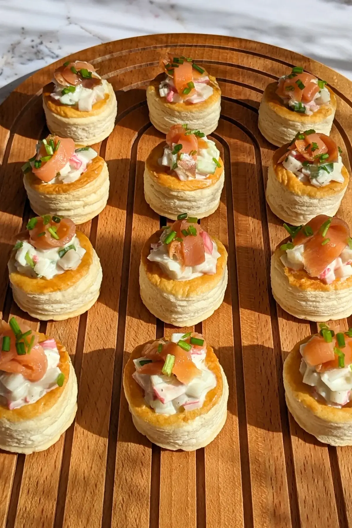 Surimi vol au vent appetizers - puff pastry vol au vent shells filled with a surimi, cucumber, and mayonnaise salad topped with smoked salmon and fresh chives. 