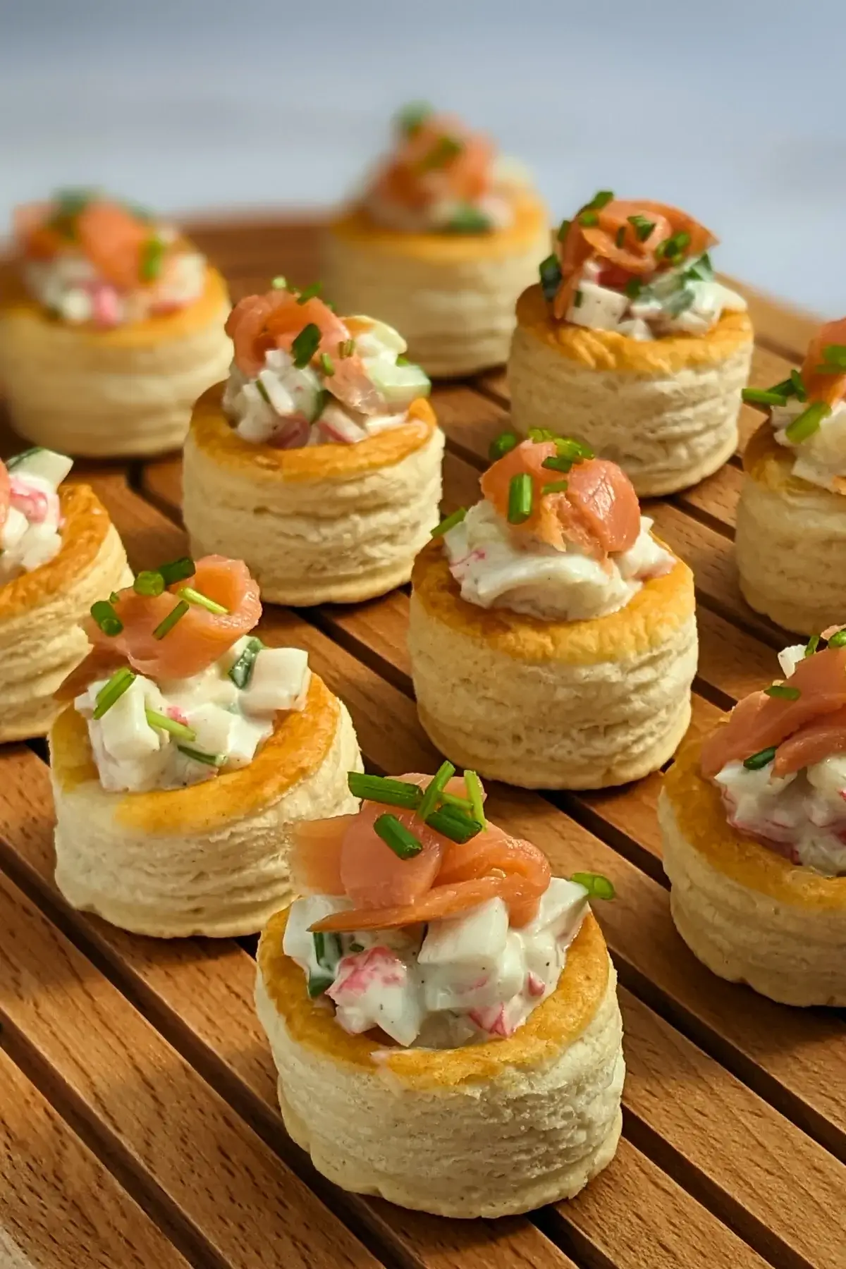 Surimi vol au vent appetizers - puff pastry vol au vent shells filled with a surimi, cucumber, and mayonnaise salad topped with smoked salmon and fresh chives.