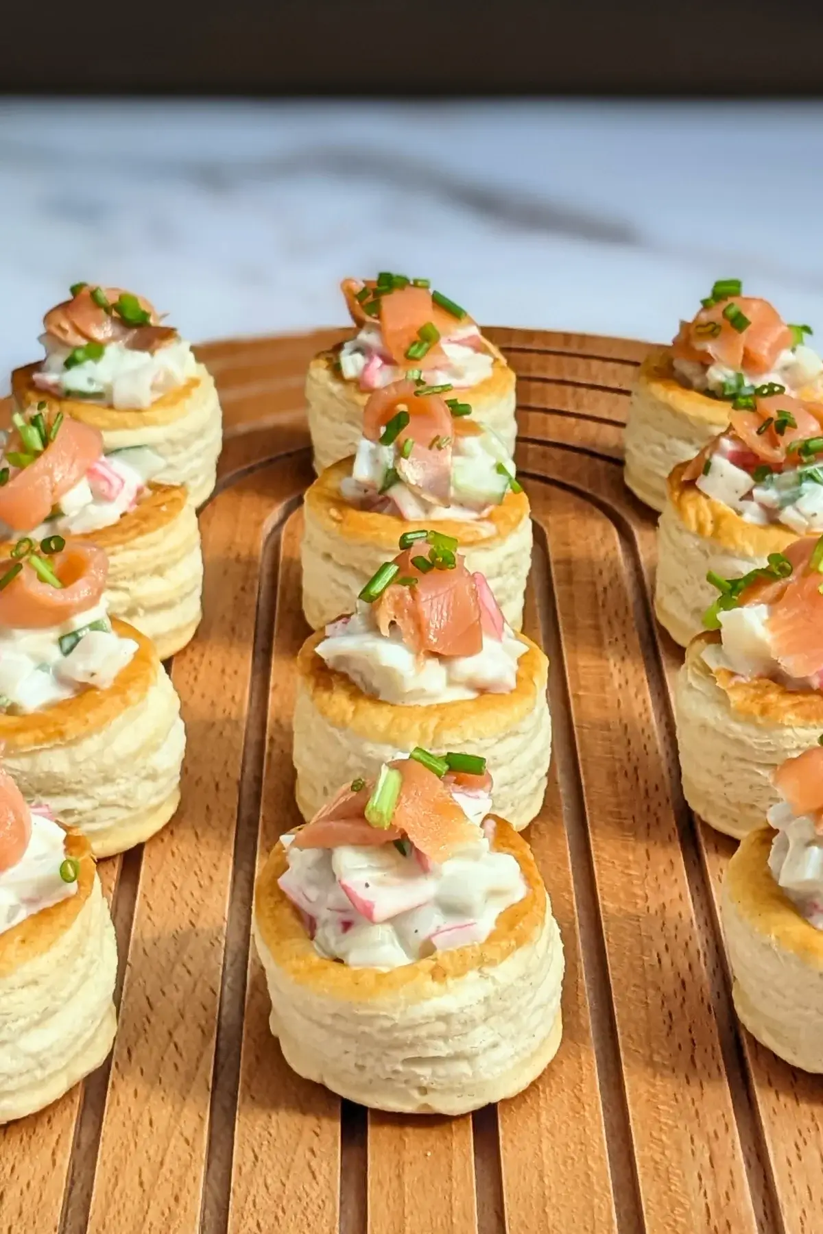 Surimi vol au vent appetizers - puff pastry vol au vent shells filled with a surimi, cucumber, and mayonnaise salad topped with smoked salmon and fresh chives.