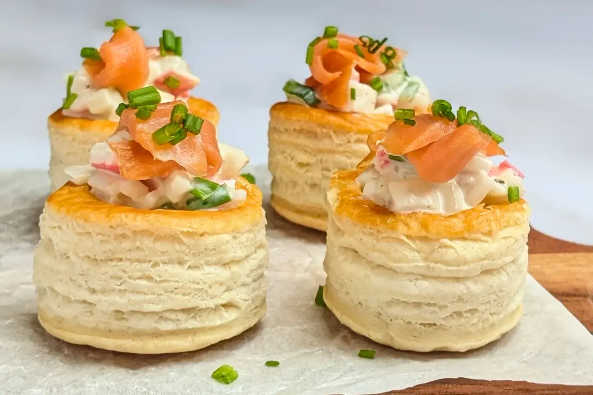 Surimi vol au vent appetizers - puff pastry vol au vent shells filled with a surimi, cucumber, and mayonnaise salad topped with smoked salmon and fresh chives.