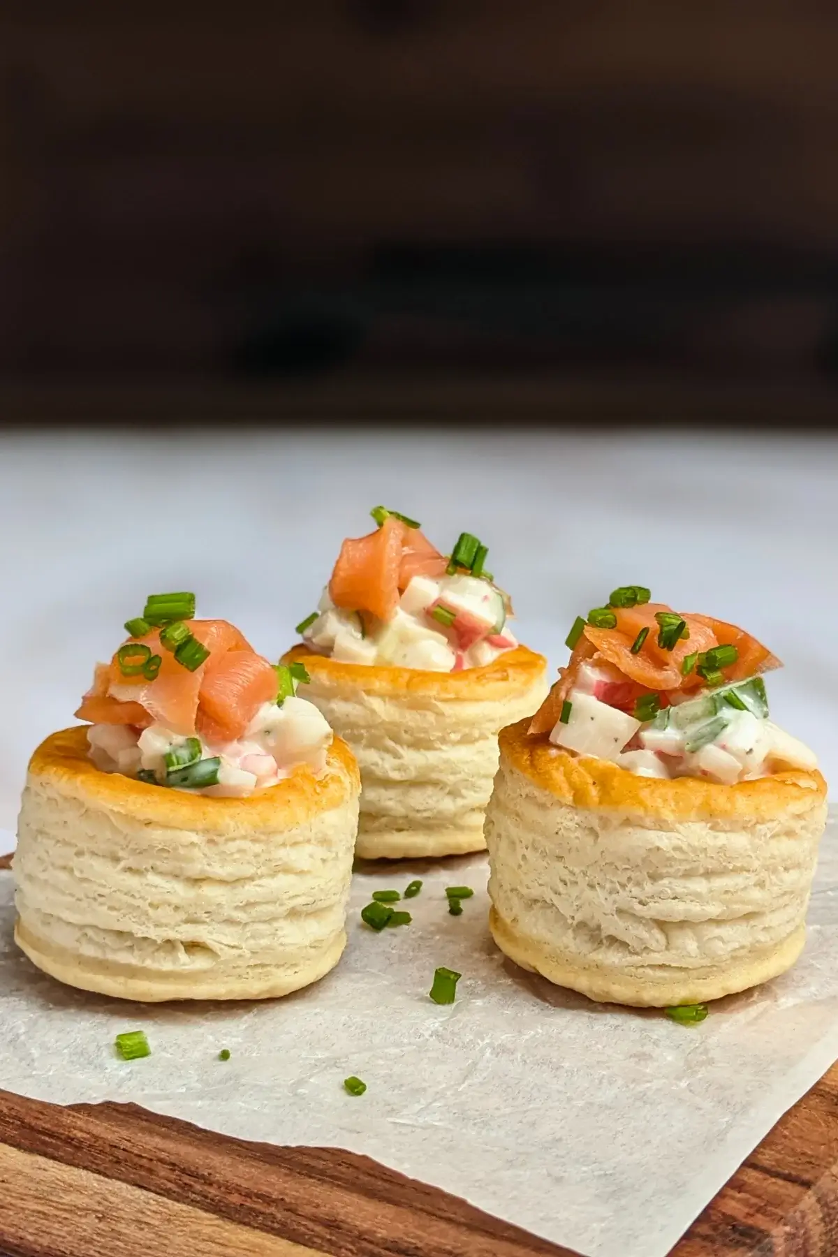 Surimi vol au vent appetizers - puff pastry vol au vent shells filled with a surimi, cucumber, and mayonnaise salad topped with smoked salmon and fresh chives. 