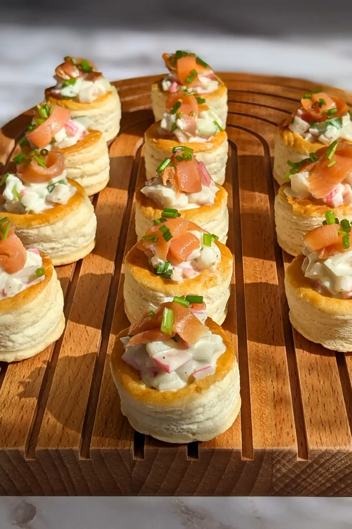 Surimi vol au vent appetizers - puff pastry vol au vent shells filled with a surimi, cucumber, and mayonnaise salad topped with smoked salmon and fresh chives. 